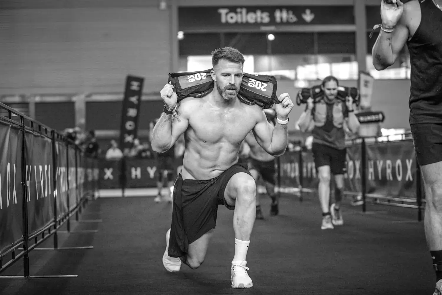 Athlete Hyrox a l'entrainement, effort intense sur fond sombre